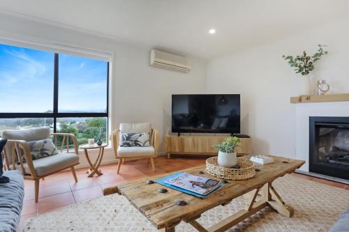 a living room with a table and a fireplace at Rosie's Seaview-Lake to ocean view in Merimbula
