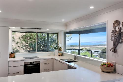 a kitchen with white counters and large windows at Rosie's Seaview-Lake to ocean view in Merimbula
