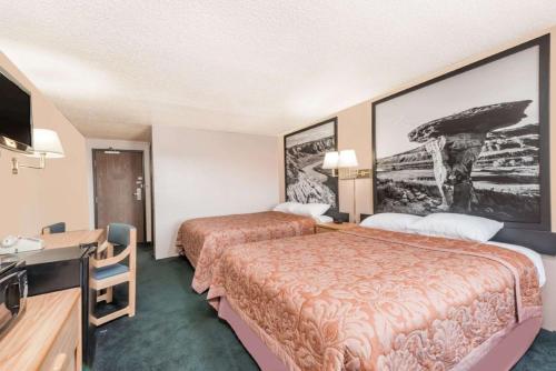 a hotel room with two beds and a desk at Glendive Lodge in Glendive