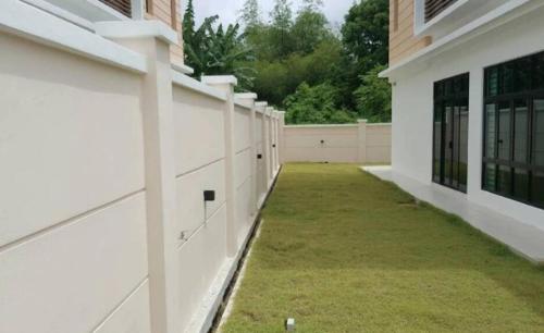 an empty courtyard of a white building with grass at Pearl Residences Sleep 27 in Batu Ferringhi