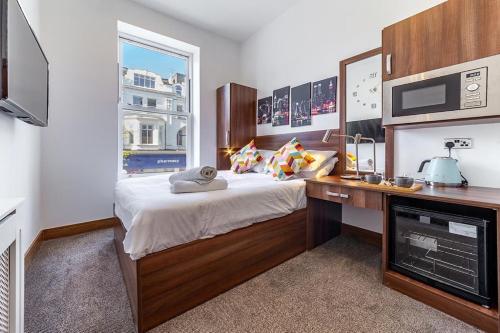 Schlafzimmer mit einem Bett, einem Schreibtisch und einem Fenster in der Unterkunft 205 Earls Court Rooms in London