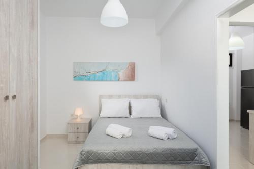 Rooftop Cosy Apartment Perfect Location في مدينة هيراكيلون: غرفة نوم بيضاء مع سرير مع وسادتين