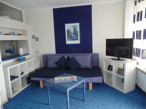 sala de estar con sofá púrpura y TV en Ferienpark Sierksdorf App 773 - Strandlage, en Sierksdorf