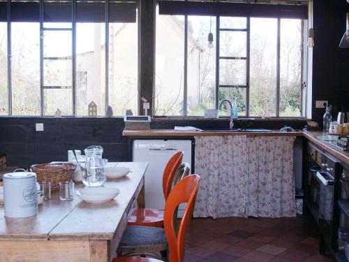 - une cuisine avec une table en bois, des chaises et des fenêtres dans l'établissement Maison de campagne charmante près du Mans avec terrasse et cadre bucolique - FR-1-410-203, à Louplande