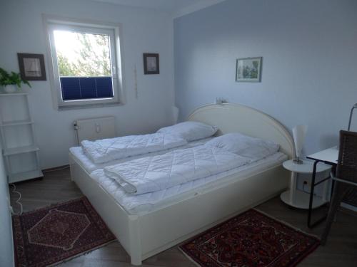 ein weißes Bett in einem Zimmer mit Fenster in der Unterkunft Objekte im Umland Neuklosterhof App 10 in Pelzerhaken
