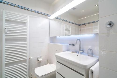 La salle de bains blanche est pourvue d'un lavabo et de toilettes. dans l'établissement Panoramic App C09-8, à Sierksdorf