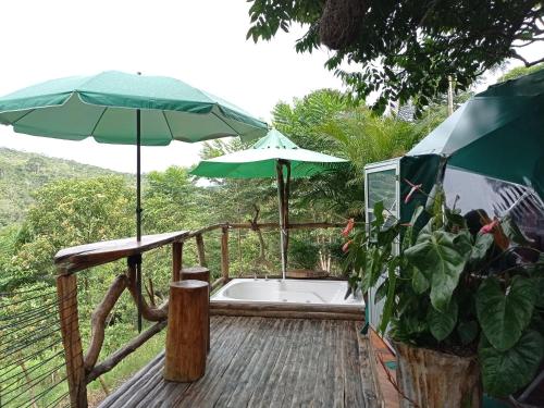 une baignoire sur une terrasse avec un parasol dans l'établissement Bellavista Experiences - Glamping, à Mocoa