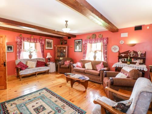 a living room with red walls and wooden floors at An Maide Bán in Cootehill