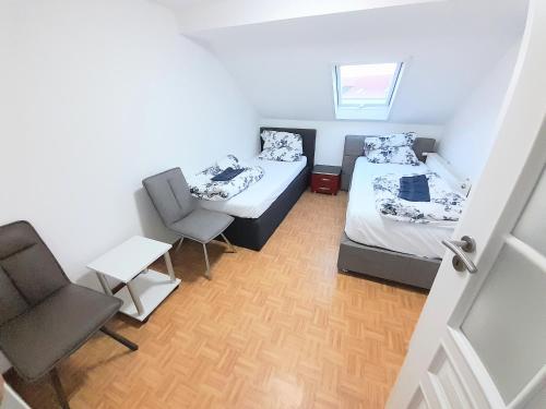 ein kleines Zimmer mit 2 Betten und einem Stuhl in der Unterkunft FMI44Apartment in Rüsselsheim