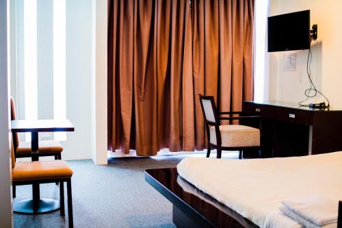 Be-ing Suites في مدينة دافاو: غرفه فندقيه بسرير ومكتب وكراسي
