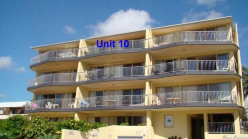 a tall yellow building with a sign that reads unit at Unit 10 Sea Eagles Apartments in Caloundra
