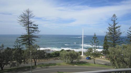 a view of the ocean with a road and trees at Unit 10 Sea Eagles Apartments in Caloundra