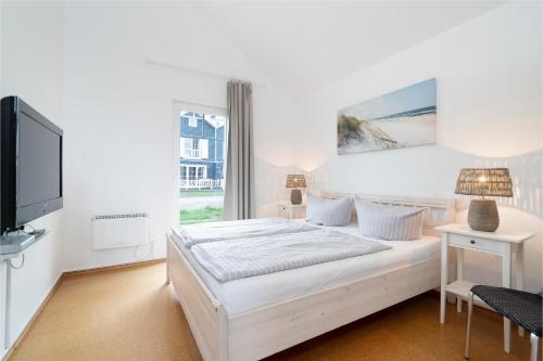 1 dormitorio blanco con 1 cama y TV en Strandpark Sierksdorf H059, en Sierksdorf