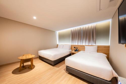 a small room with two beds and a table at Hotel Foret The Spa in Busan