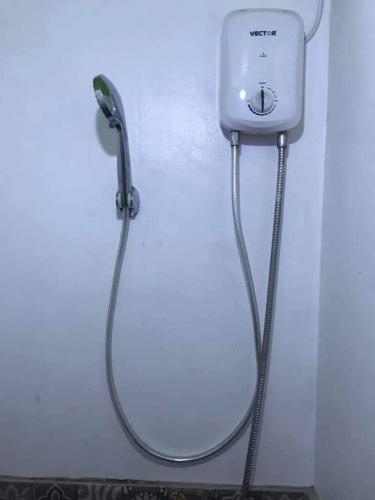 a shower with a hose attached to a wall at Jen's place in Antipolo