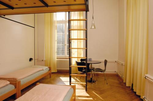 een kamer met 2 bedden, een tafel en een raam bij Solothurn Youth Hostel in Solothurn