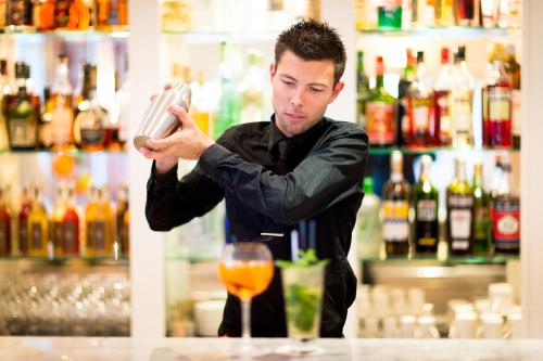 a man standing at a bar with a drink at Hôtel Les Mouettes - Teritoria in Ajaccio