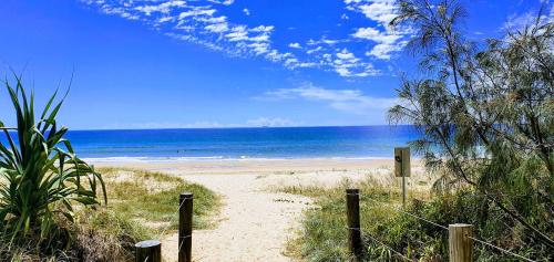 a path to a beach with the ocean in the background at Serene Beachside Apartment in Marcoola