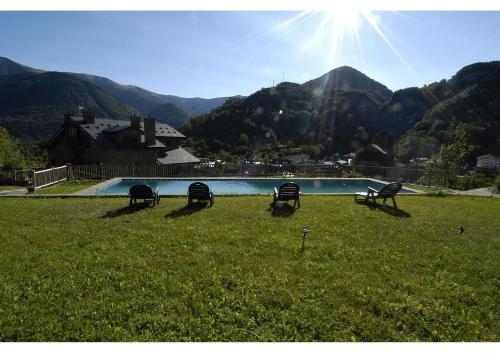 a group of benches sitting in the grass near a pool at Hotel Rural El Portón de Murillo in Broto