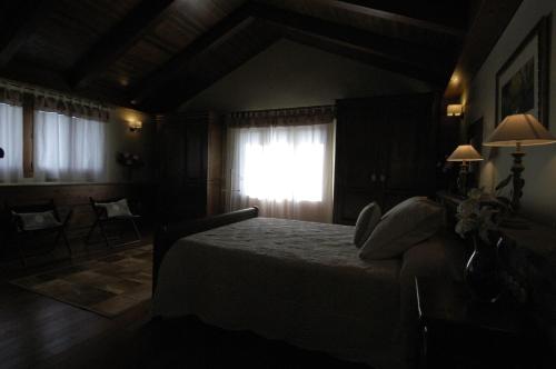 a dark bedroom with a bed and a window at Hotel Rural El Portón de Murillo in Broto