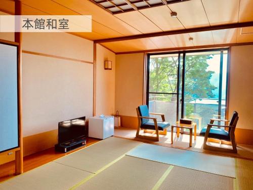 箱根七福荘 في هاكوني: غرفة معيشة مع كراسي وتلفزيون بشاشة مسطحة
