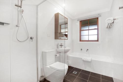 a bathroom with a toilet, tub, sink and shower at Bellevue Accommodation in Kiama