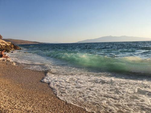 a beach with a wave breaking on the shore at Olea Residence, Luxury sea view apartment with private beach in Palasë