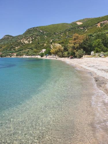 a beach with clear blue water and a mountain at Olea Residence, Luxury sea view apartment with private beach in Palasë