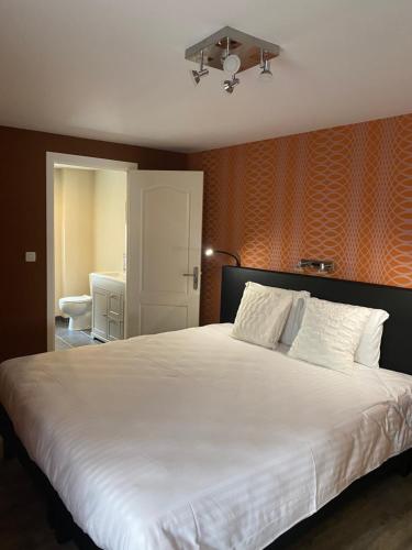 布永的住宿－LA CACHETTE Maison 3Ch 3SdB Salon Wifi，一间卧室配有一张白色大床和橙色墙壁