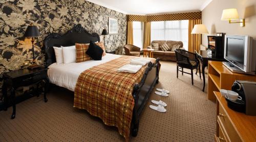 a hotel room with a bed and a television at Mercure Bristol North The Grange Hotel in Bristol