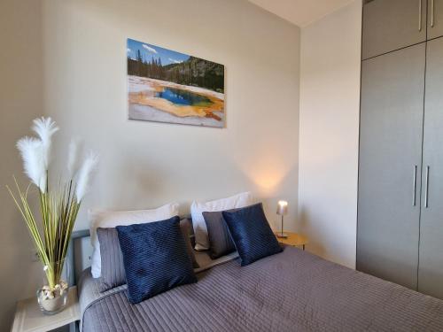 a bedroom with a bed with blue pillows at MANO JŪRA 2 SILVER in Palanga