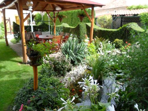 a garden with a pergola and a table and chairs at Hajnalka vendégház in Bük