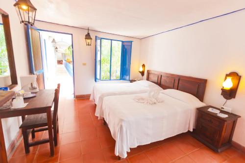 a bedroom with two beds and a table and a desk at Posada del Cafeto in Xalapa