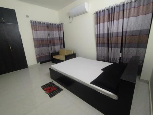 a bedroom with a bed in a room with curtains at Rose Garden Guest House in Khulna