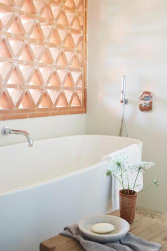 ein Badezimmer mit Badewanne und einem Tisch mit Blumen in der Unterkunft Borgo 69 Villas & Suites in Foiano della Chiana