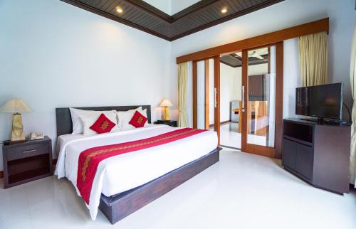 a bedroom with a large bed and a television at Kayu Suar Bali Luxury Villas & Spa in Sanur