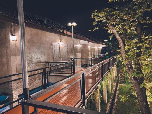 a walkway with lights on a building at night at บ้านต้นไม้โฮมสเตย์อุทัยธานี in Uthai Thani