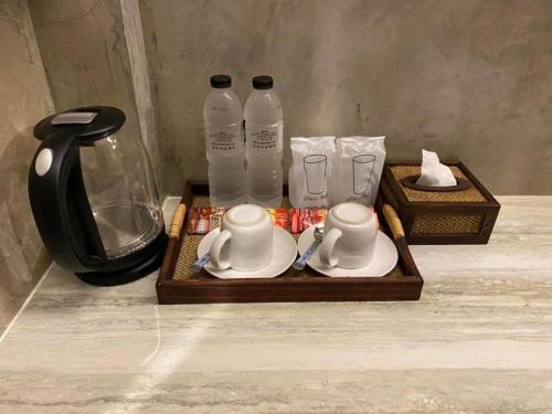 a wooden tray with two cups and bottles of water at บ้านต้นไม้โฮมสเตย์อุทัยธานี in Uthai Thani