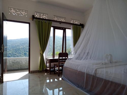 a bedroom with a bed with a desk and a window at Aris Homestay and Warung Made in Munduk