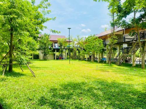 a large yard in front of a building with trees at บ้านต้นไม้โฮมสเตย์อุทัยธานี in Uthai Thani