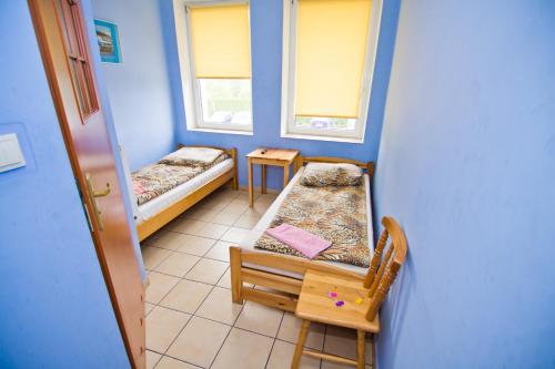 a room with two beds and a table and two windows at Hotelik Bej in Tuszyn