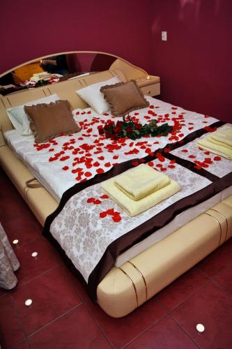 a large bed with red flowers on it at Hotelik Bej in Tuszyn