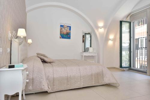 a white bedroom with a bed and a window at Sirena Apartment in Minori