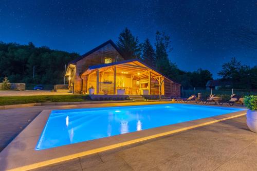 a swimming pool in front of a house at night at Holiday Home Mali Medo in Gospić