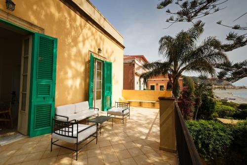 a patio with chairs and a building with green shutters at Maison Canopée in Messina