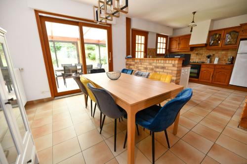 cocina y comedor con mesa de madera y sillas en La Villa aux Oliviers en Eu