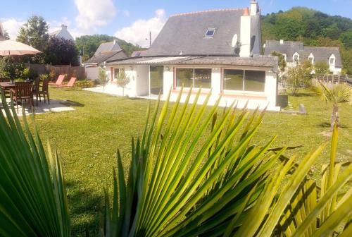 a house with a green yard with a palm tree at Maison à 30m de la plage avec grand jardin in Plérin