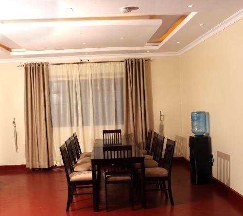 a dining room with a table and chairs and a television at The Meru Manor in Meru