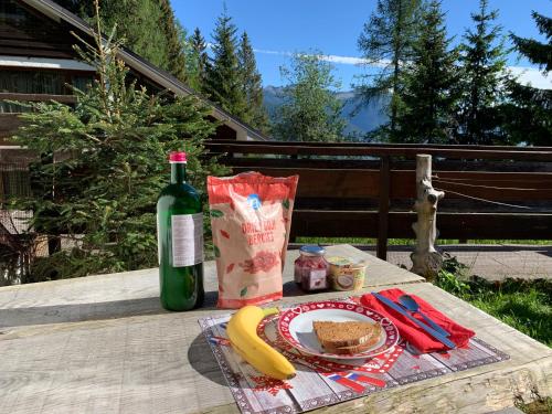 a picnic table with a plate of food and a bottle of wine at Casetta dei Cuori - Alpine Style Cozy Apartment in Folgarida