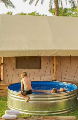 a young boy sitting in a pool of water at Sky Glamping boutique in Moshav Ramot
